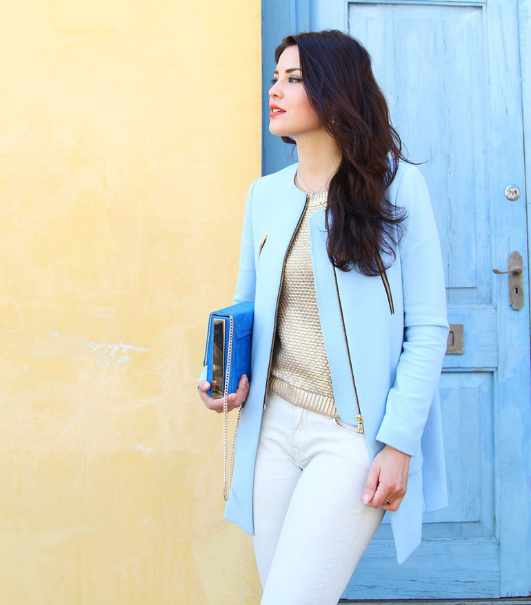 Chica morena posando en la calle con una chaqueta color azul pastel y un bolso de color azul klein