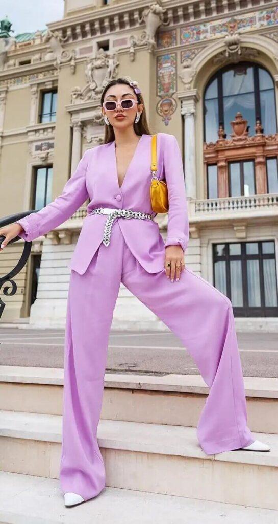 Chica con un traje pantalón de color lavanda posando en unas escaleras en la calle